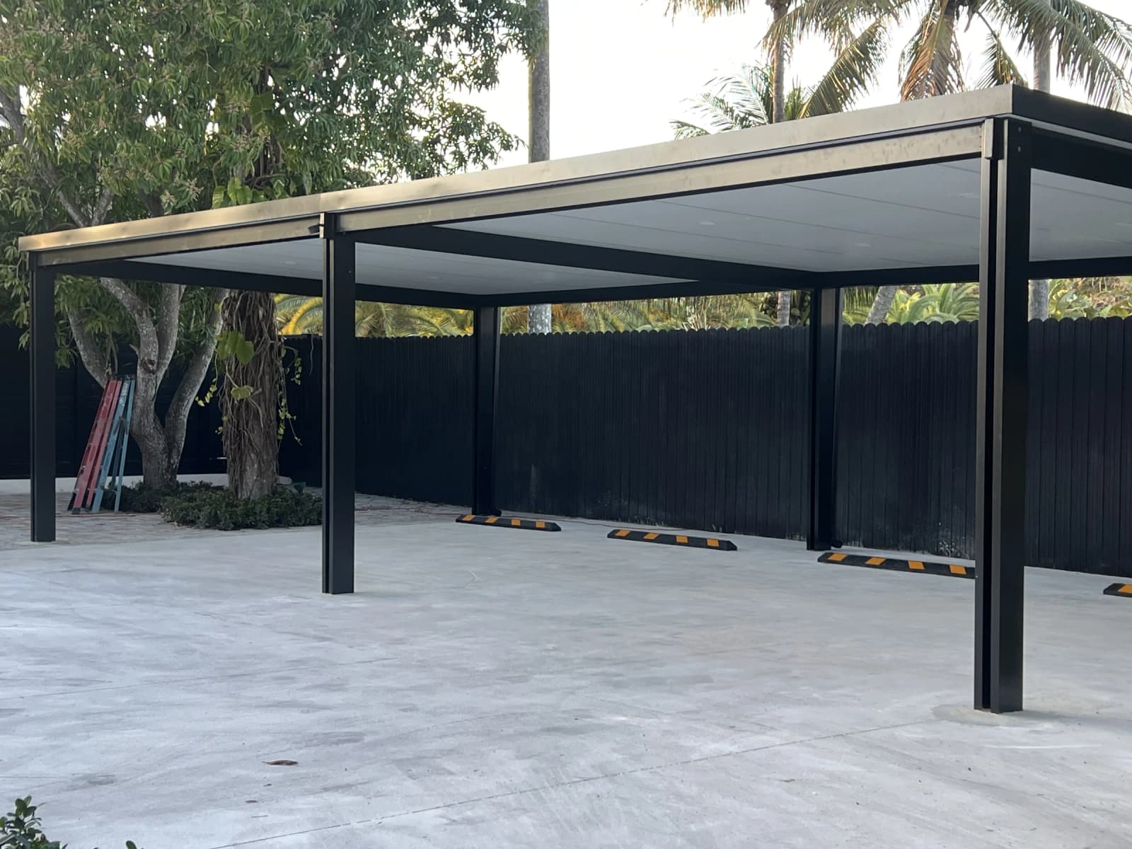 Black aluminum pergola carport over a paved driveway